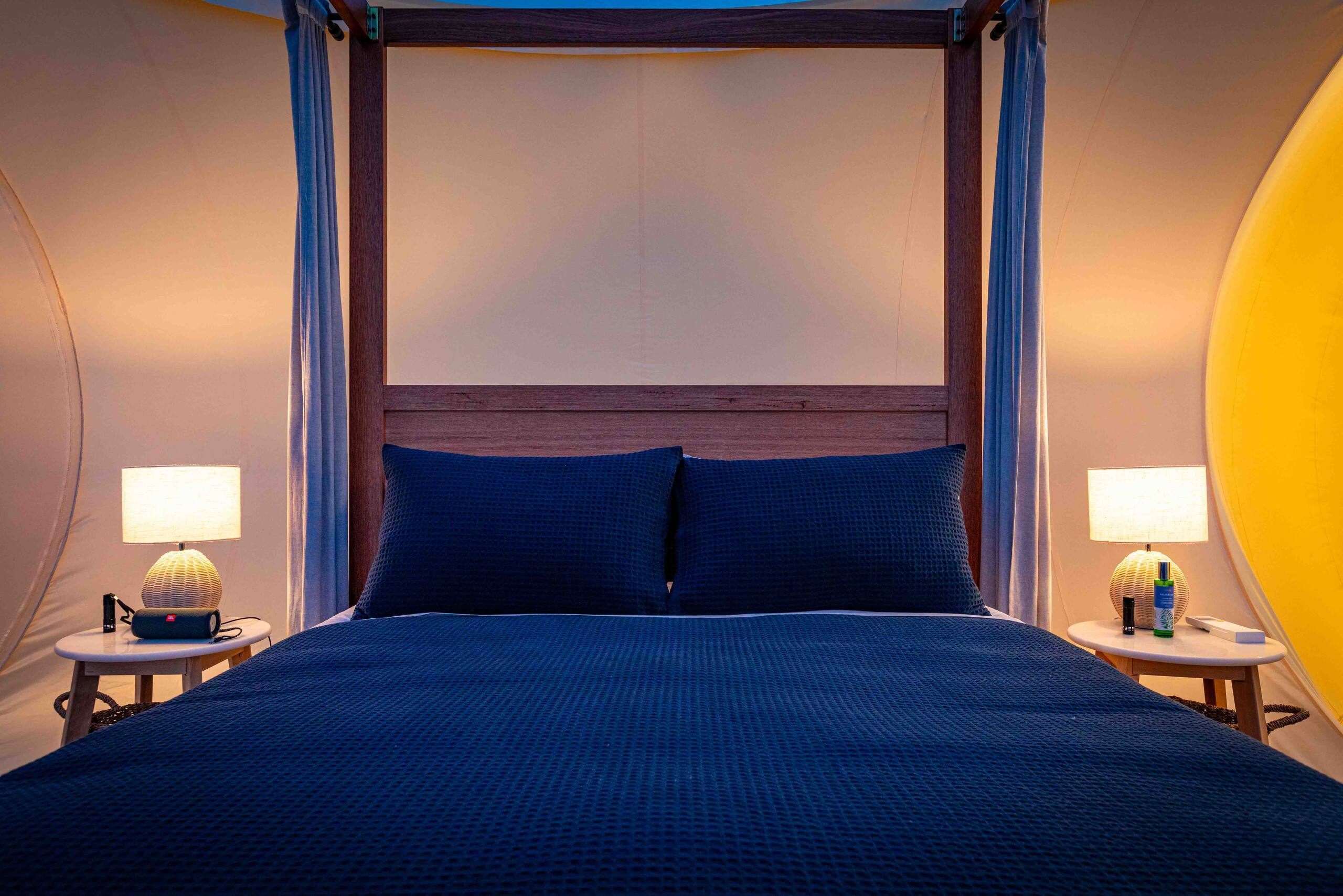 The four-poster bed with twin bedside lamps glowing